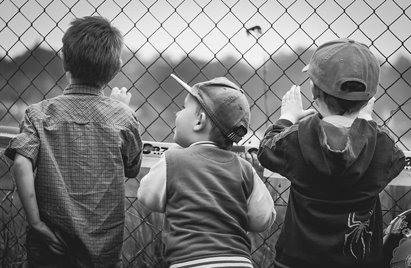children leaning on the fence and watching across it
