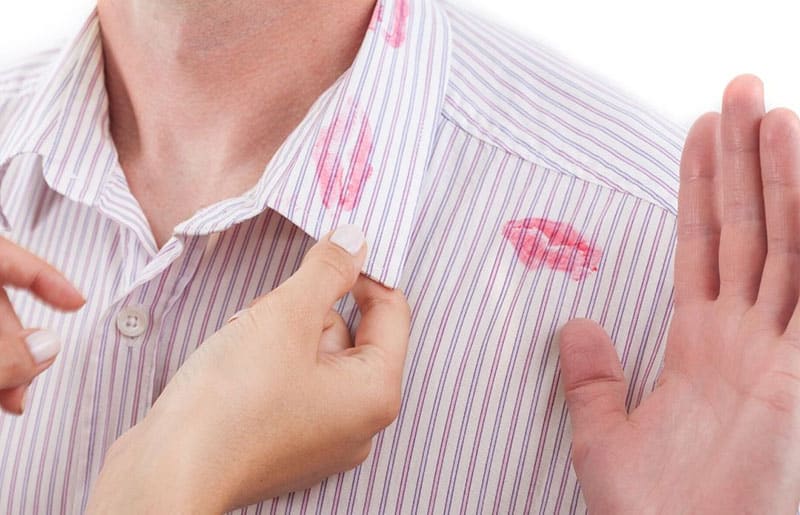 collar with lipstick mark held by a hand with hand sign from man denying 