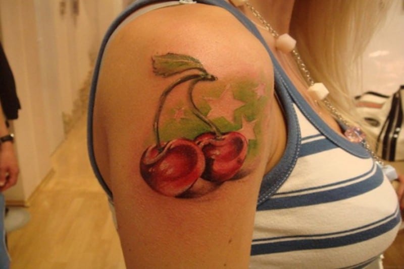 due ciliegie rosse con stelle tatuaggio sul braccio