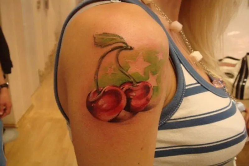 two red cherries with stars tattoo on arm