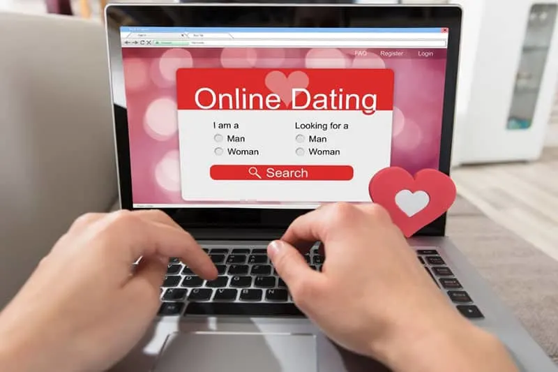 computer screen showing an online dating site with a hand of a person 