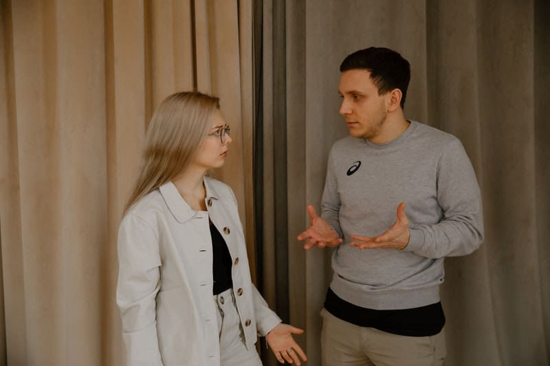 couple arguing near the beige and gray curtains