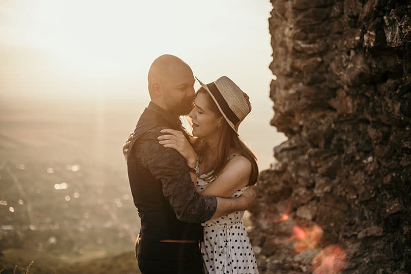 couple beside the big rocks hugging each other with the city overlooking