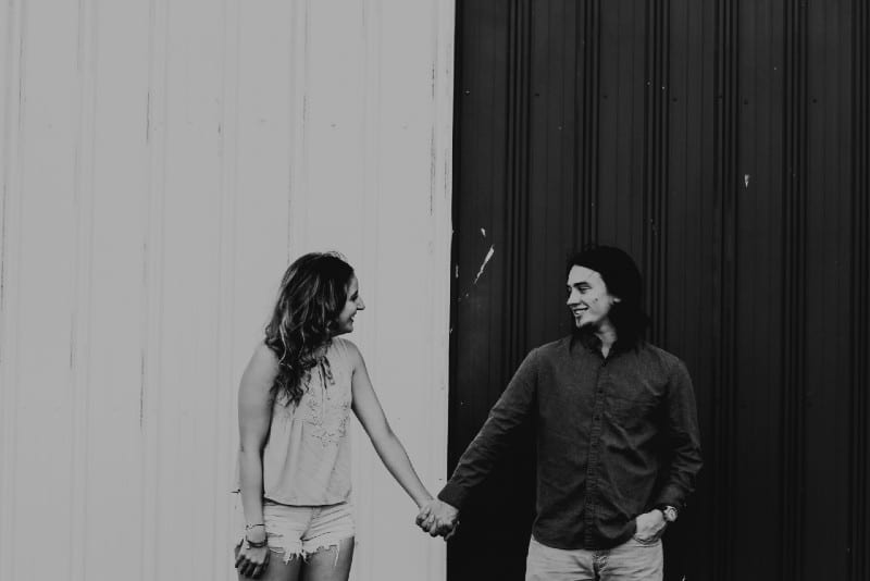 man and woman holding hands in grayscale photography