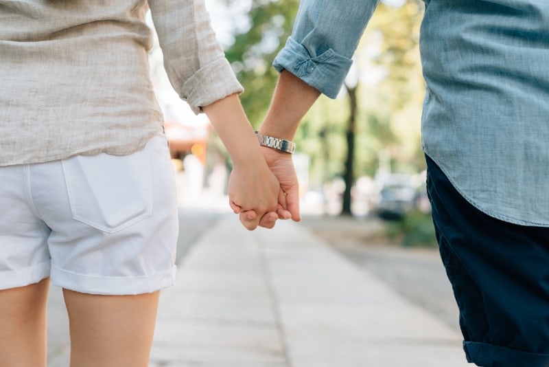 man and woman holding hands together in walkway during daytime