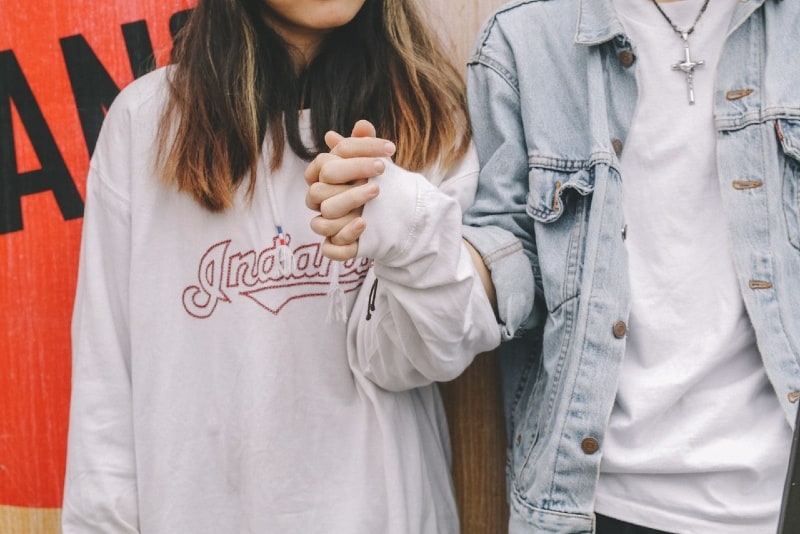 woman in sweatshirt and man in denim jacket holding hands