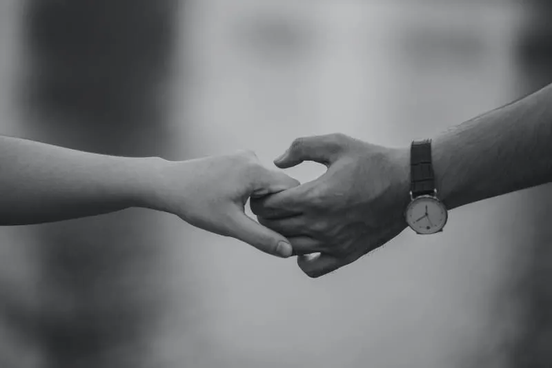 monochrome photo of man and woman holding hands