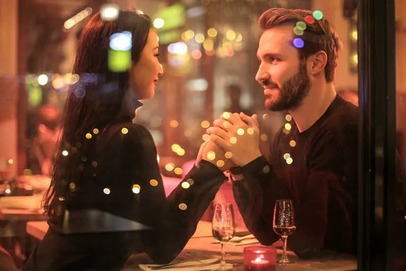 couple holding hands near the window in the restaurant