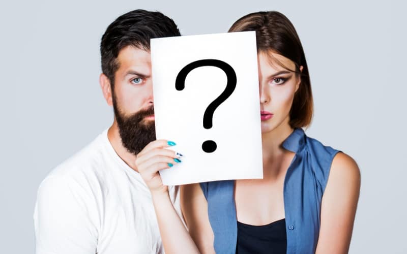 Couple holding question mark paper in front of them