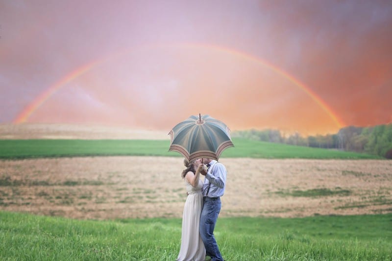 uomo e donna che tengono l'ombrello e si baciano all'aperto
