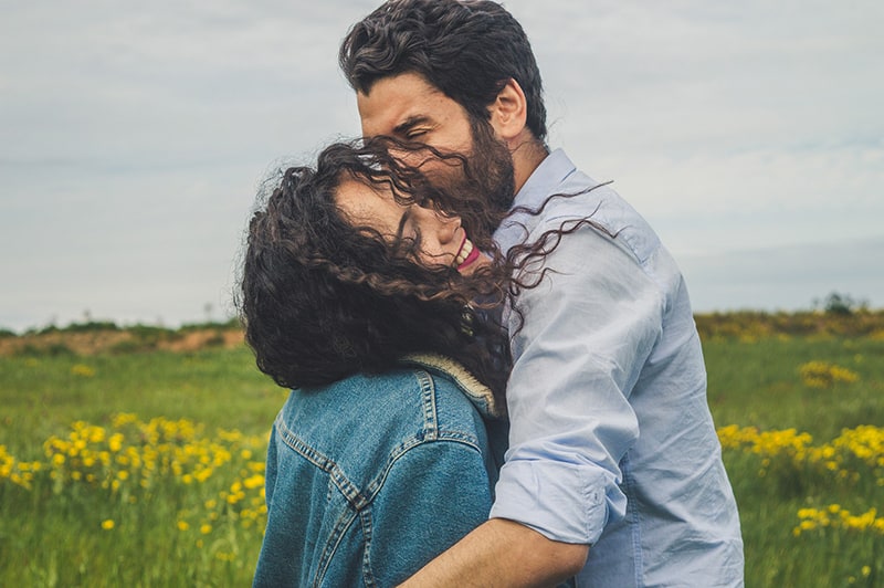 couple hugging each other while standing in flower field