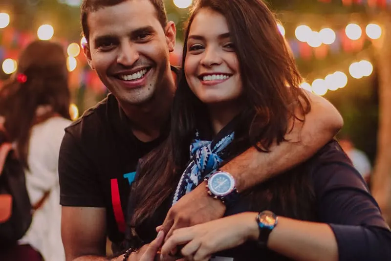 couple hugging and holding hands in front of festival lights