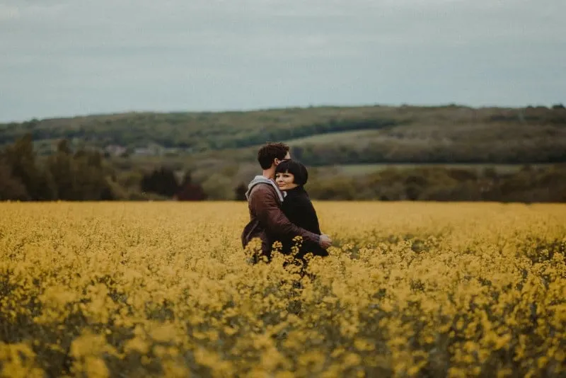 man and woman hugging near yellow flowers