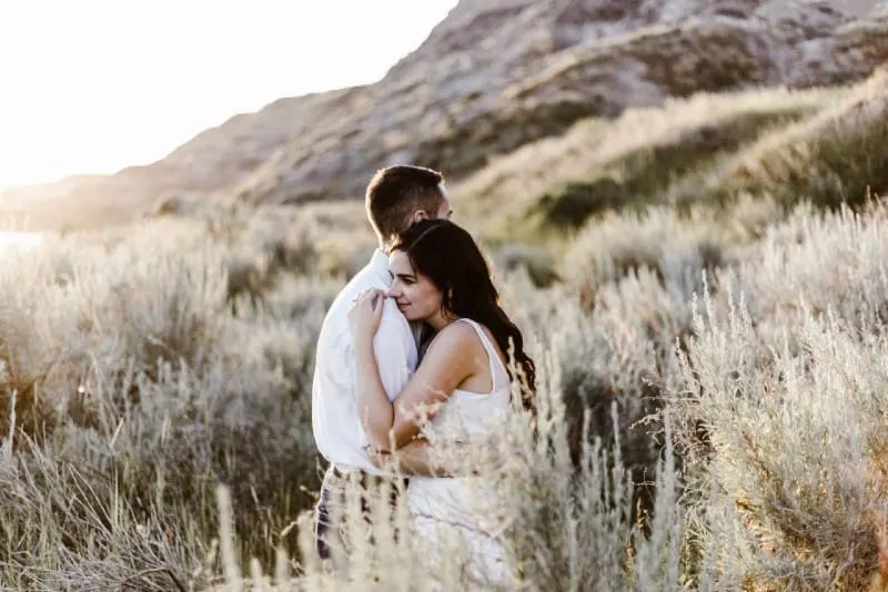 man in white shirt and woman in white dress hugging