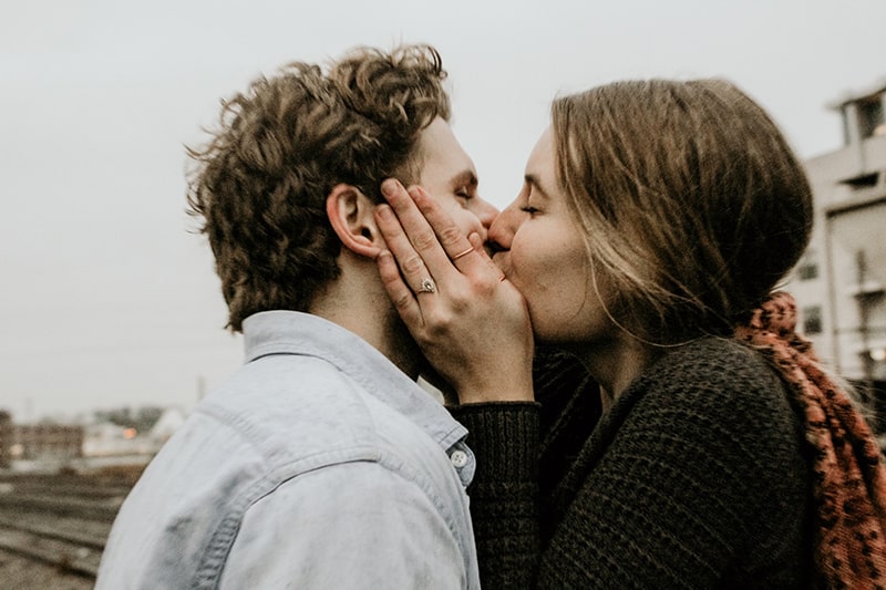 pareja besándose bajo nubes grises