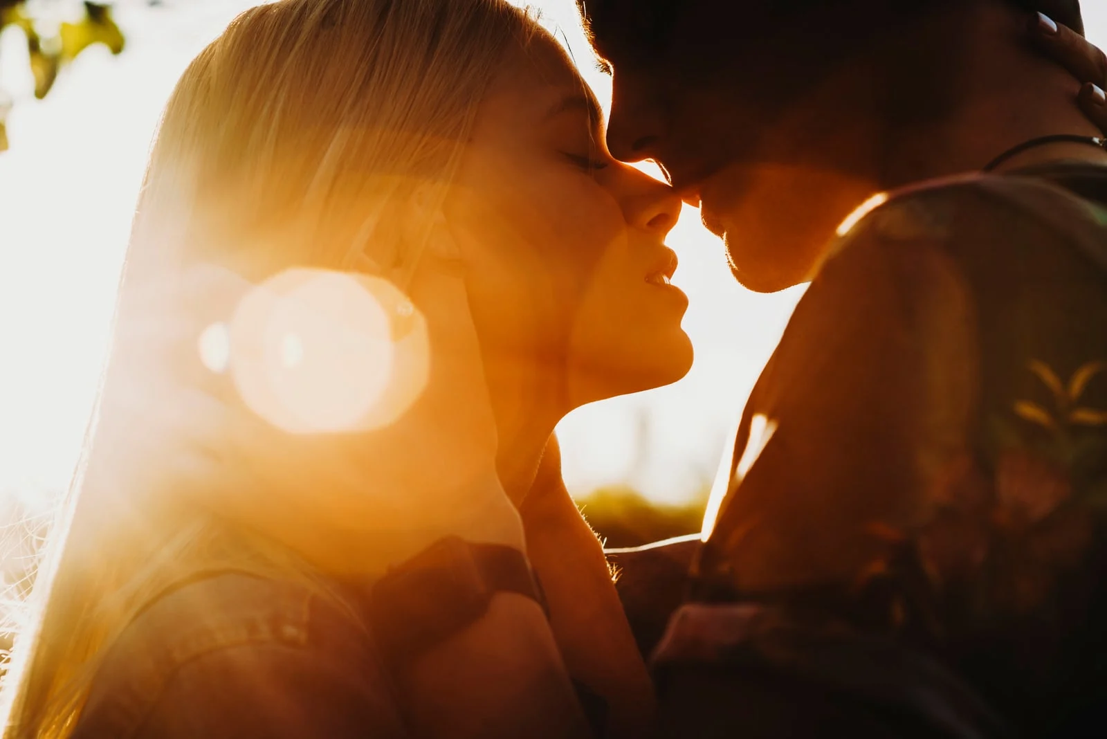 couple kissing against sunset light