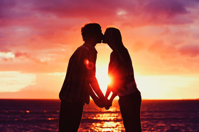 couple kissing at sunset by the sea