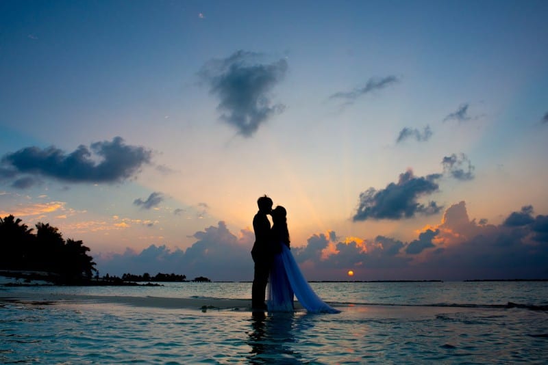 silhouette of man and woman kissing between body of water
