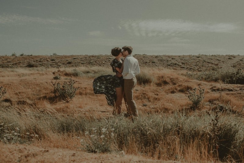 uomo e donna che si baciano in un campo durante il giorno