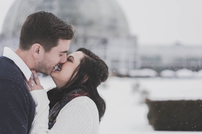 uomo e donna che si baciano in tempo di neve