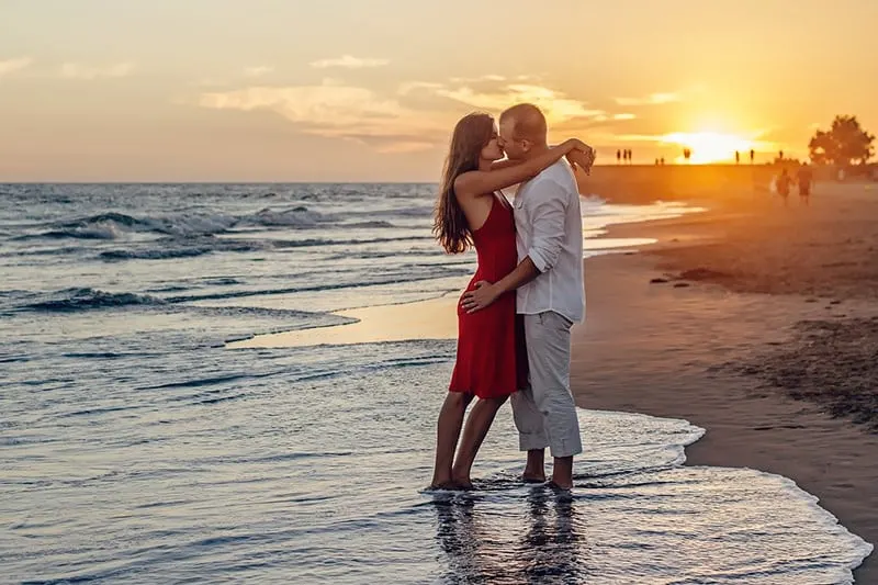 couple kissing on sunset while standing in the ocean