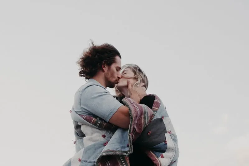 man and woman wrapped in blanket kissing outdoor