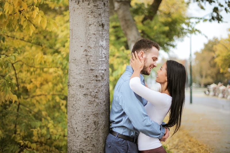 pareja apoyada en un árbol