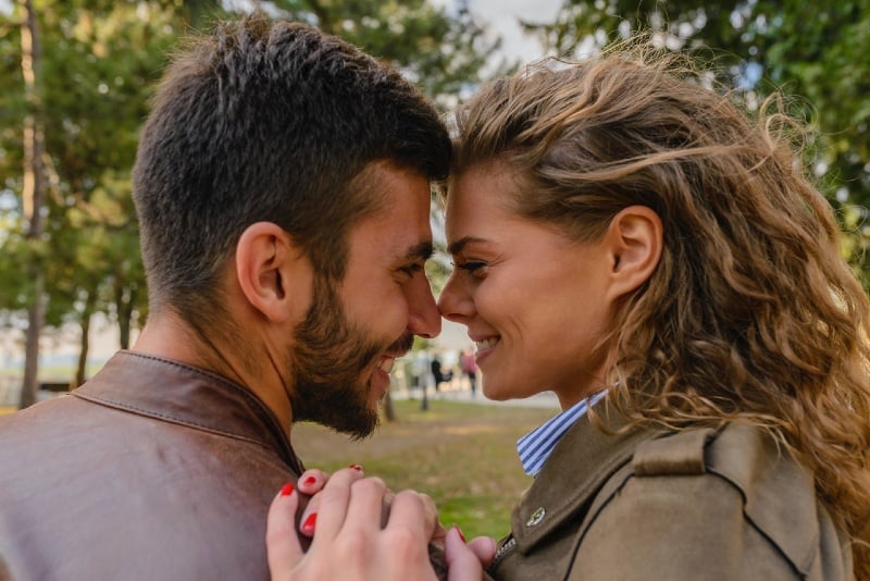 man wearing brown leather jacket looking at woman