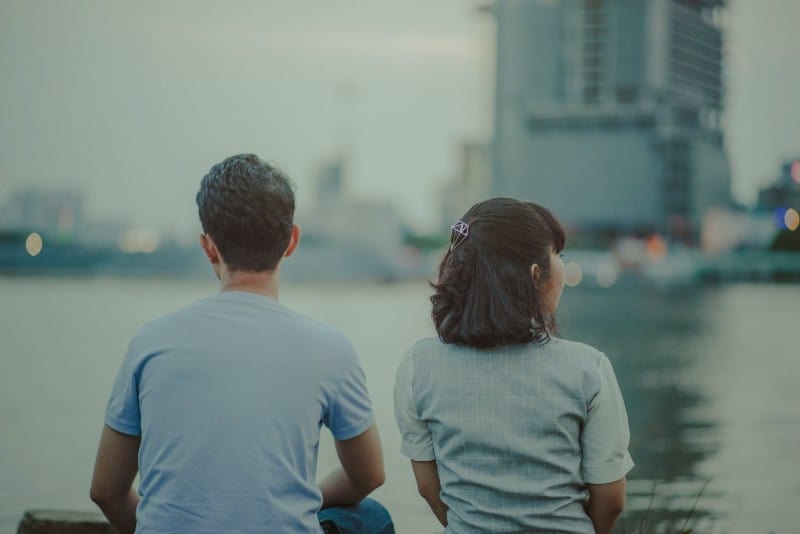 hombre y mujer mirando el agua y edificios de hormigón