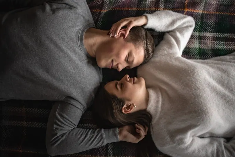 man and woman lying on checked blanket and cuddling