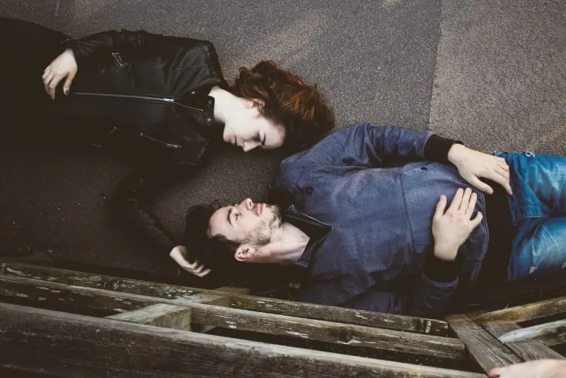 man and woman lying on concrete making eye contact