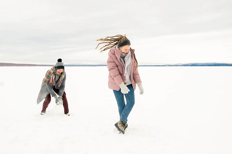 coppia che gioca con la neve in mezzo alle bianche pianure innevate