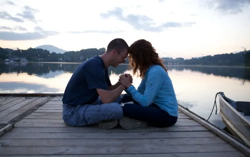 Couple praying together on a bridge