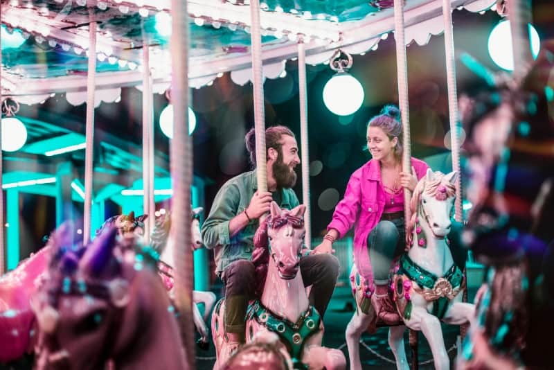 man and woman holding hands riding a carousel