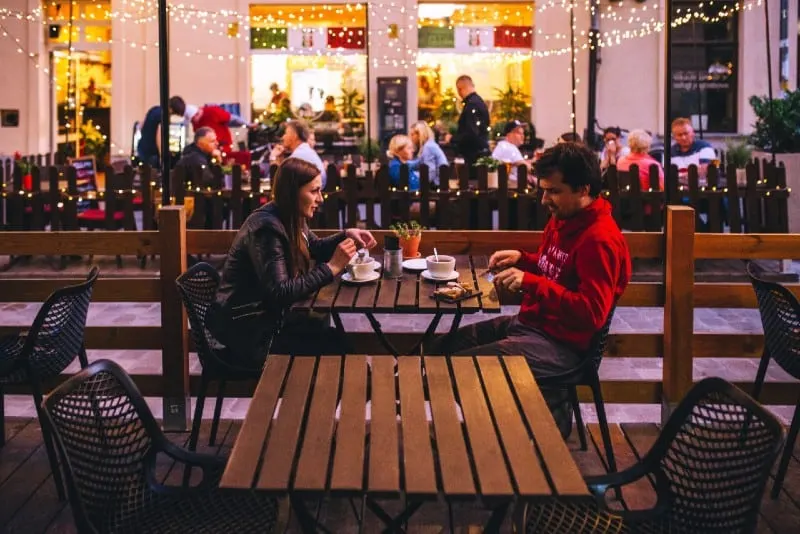 man and woman drinking coffee and sitting at table outdoor