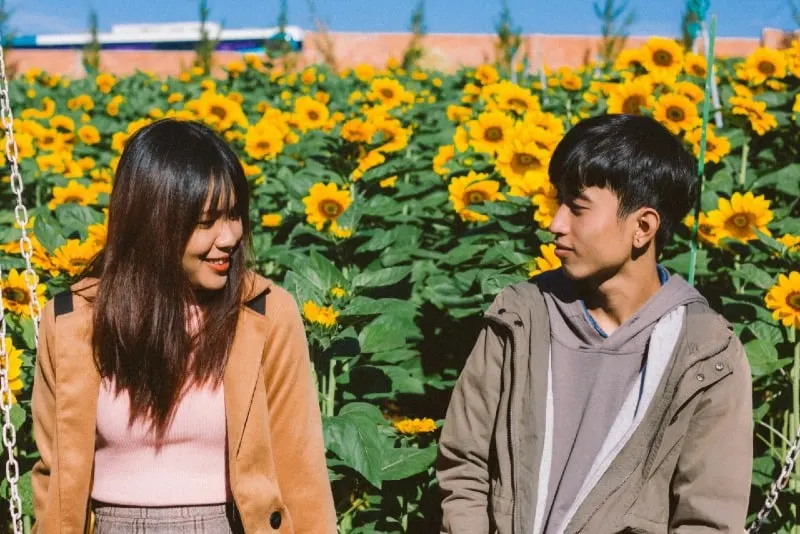 woman and man sitting near sunflowers during daytime
