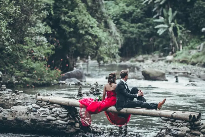 couple sitting on wooden bridge in forest