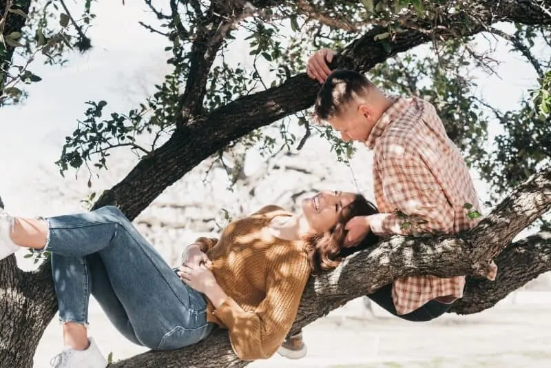 man looking at woman while sitting on tree