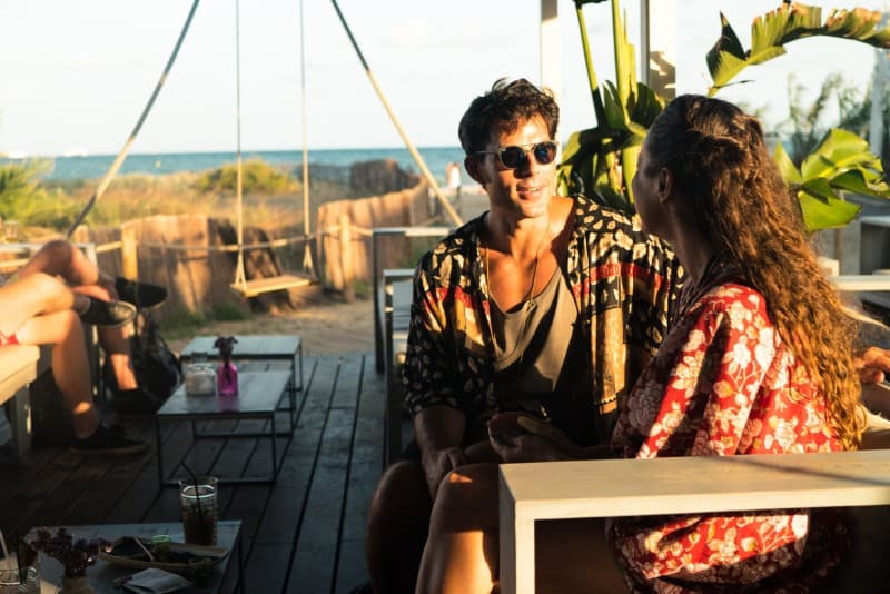 hombre con gafas de sol y mujer sentados en una mesa al aire libre