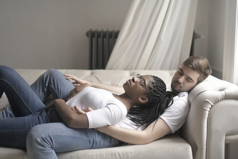 coppia che dorme sul divano con la donna sopra l'uomo