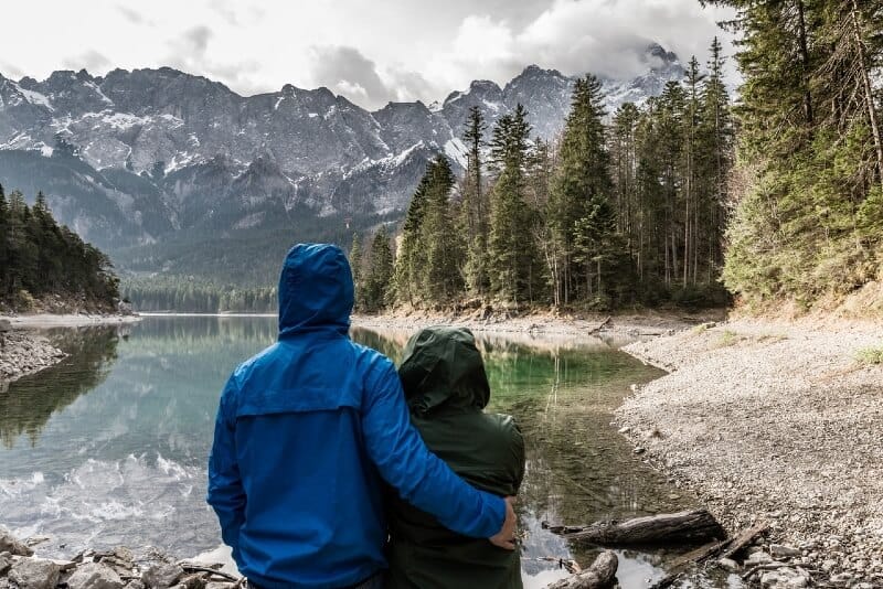 man and woman with hoodie jackets standing near water