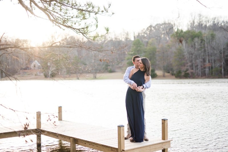 man and woman hugging while standing on wooden dock