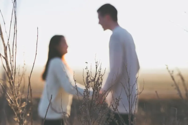man and woman in white sweaters standing on grass