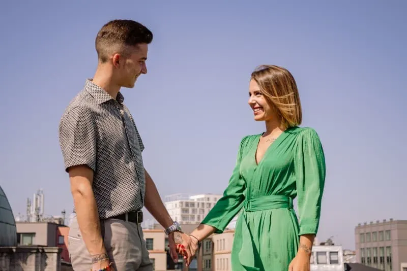 man and woman holding hands and standing on rooftop