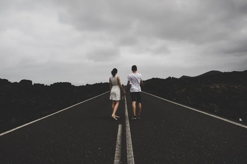 man and woman standing on the road and holding hands