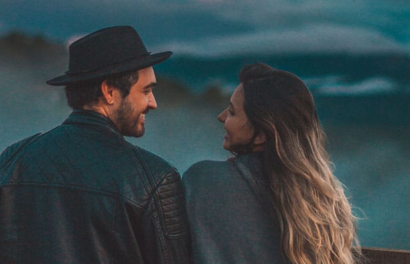 casal a olhar um para o outro, mostrando o céu azul escuro e enevoado