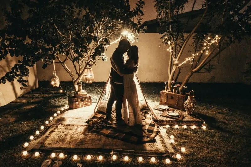 man and woman hugging while surrounded by tealights