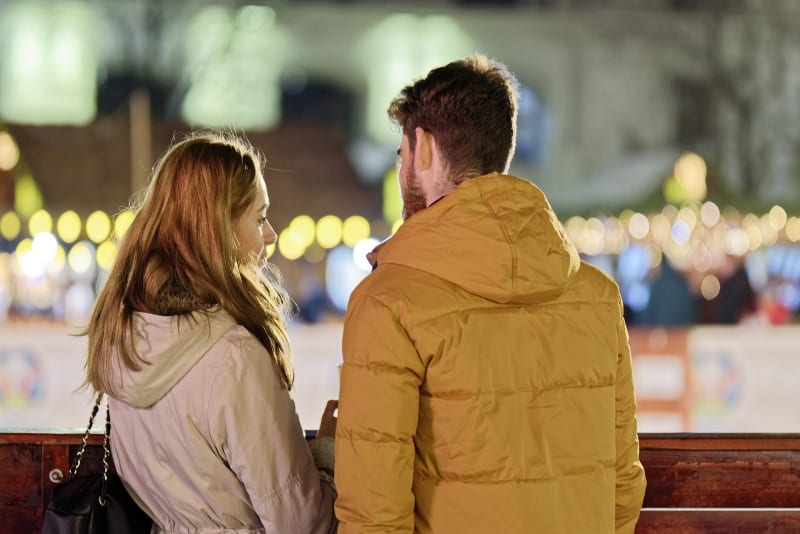 mujer y hombre con chaqueta amarilla hablando al aire libre