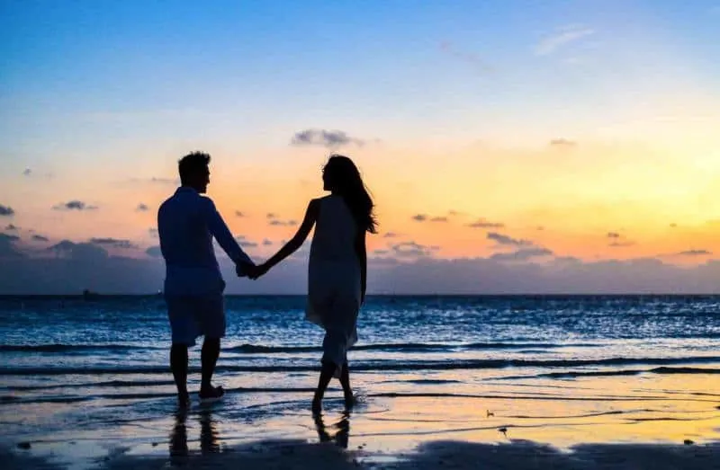 Romantic man and woman couple-walking on-the beach during sunset time