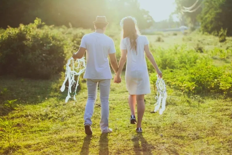 man and woman holding white dream catchers and walking 